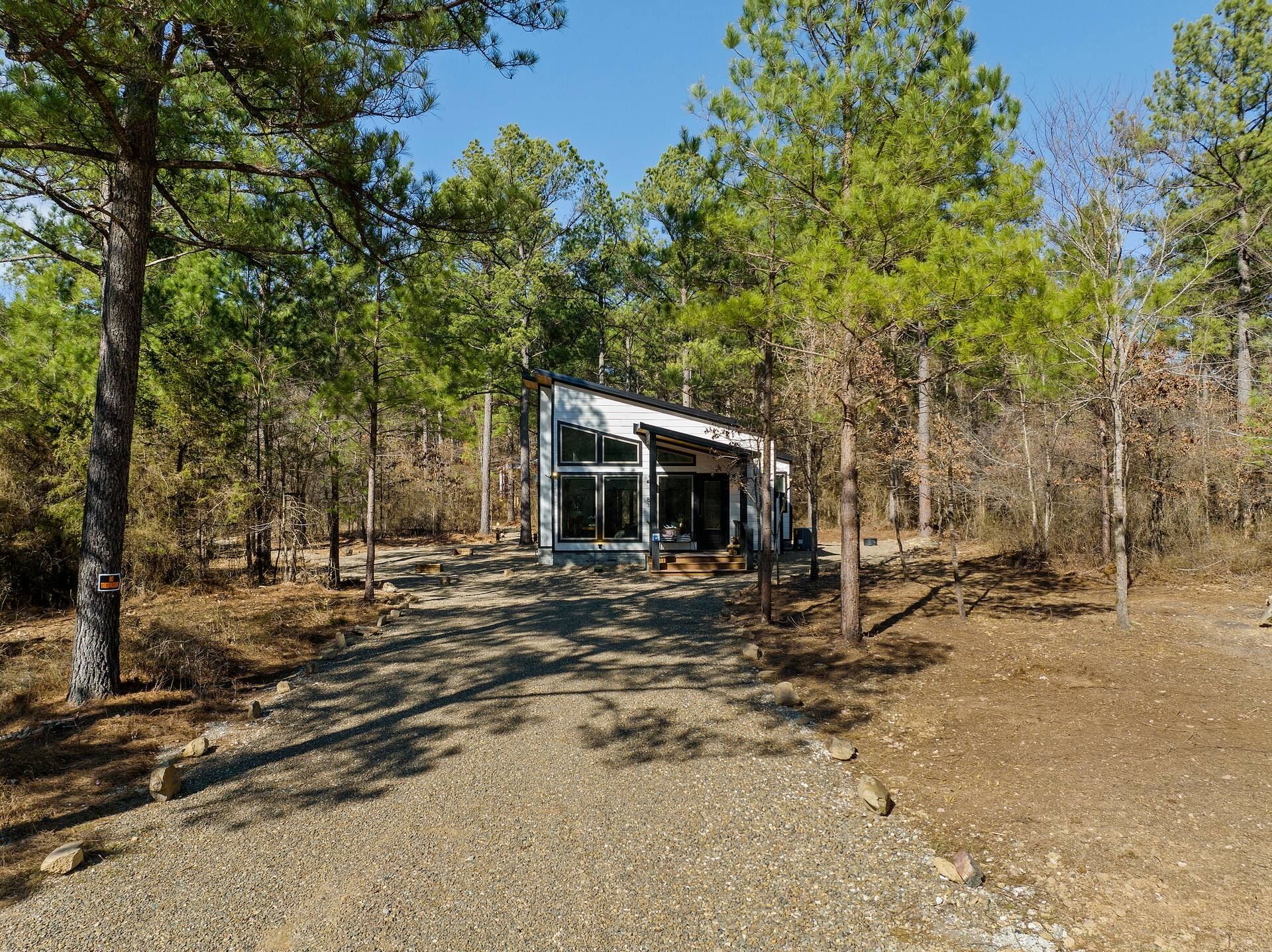 Gravel drive leading to the cabin under a blue sky and tall pines
