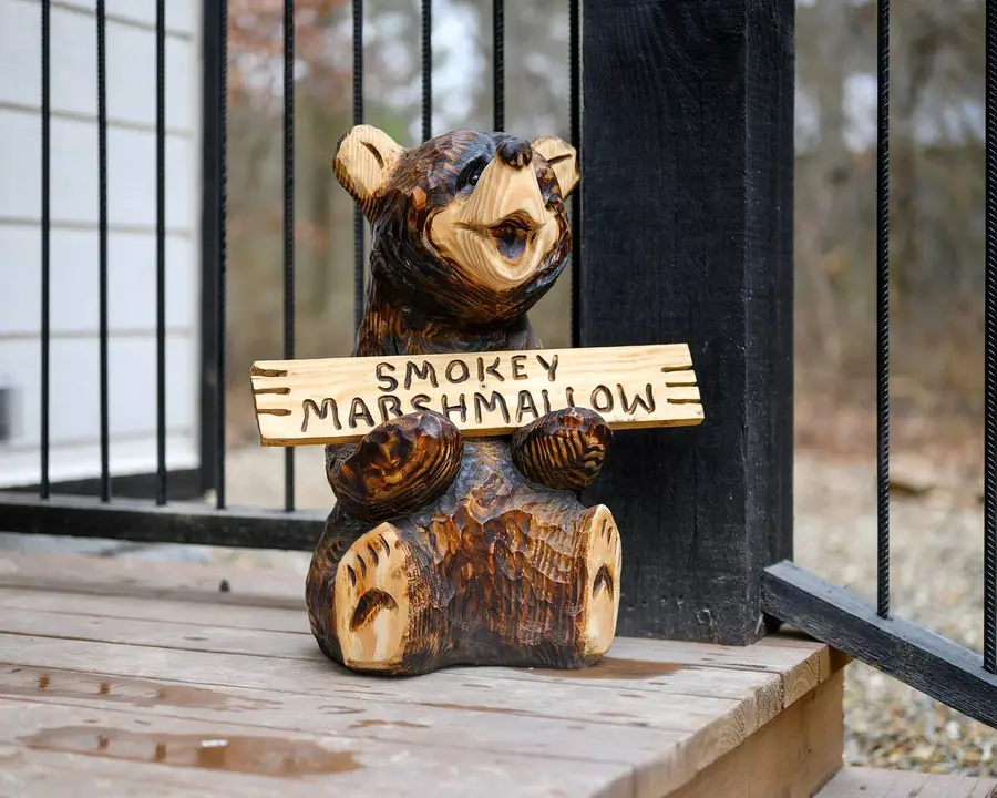 Carved wooden bear holding a Smokey Marshmallow sign on the porch