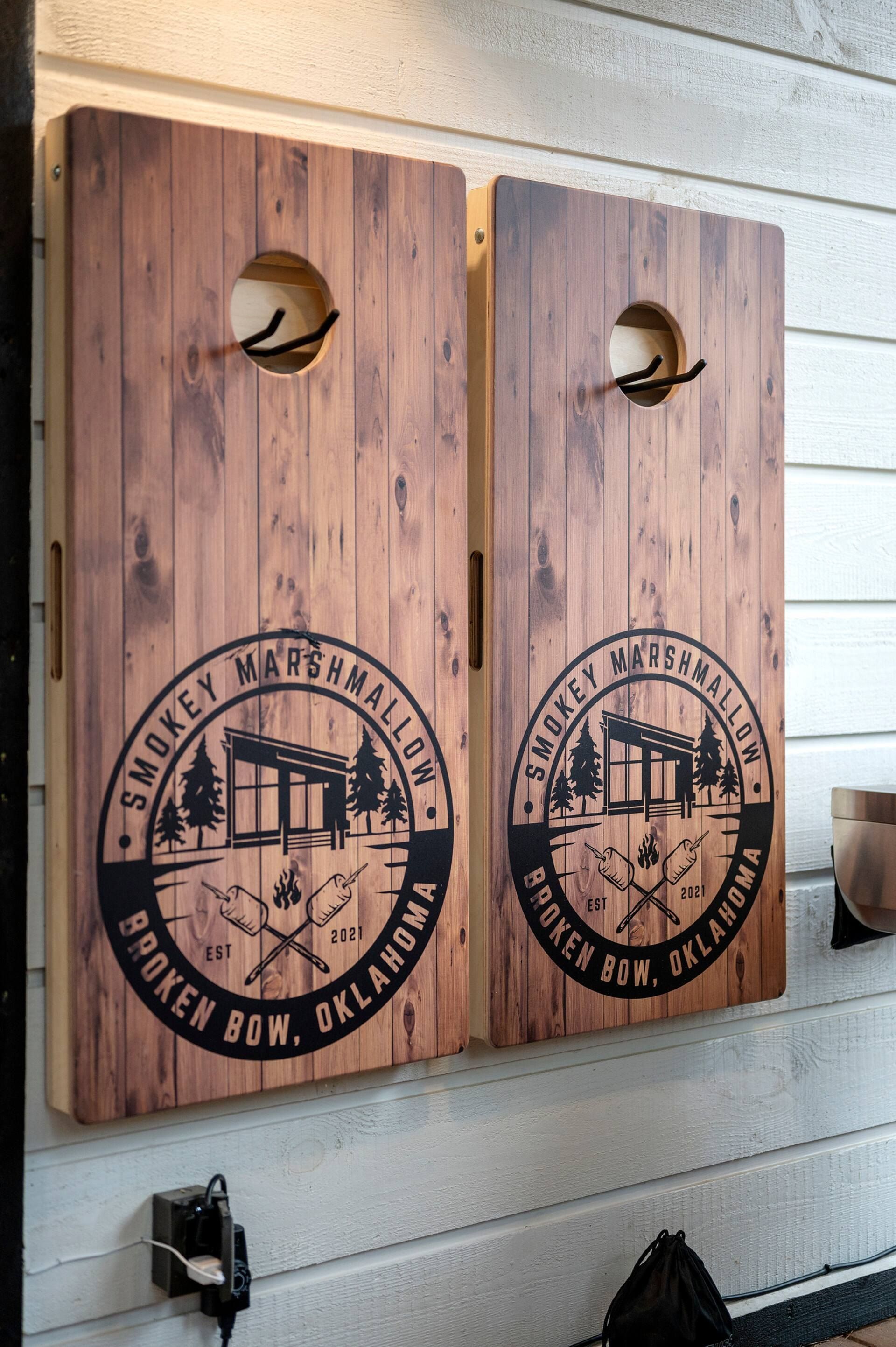 Two Smokey Marshmallow branded cornhole boards hanging on the cabin wall
