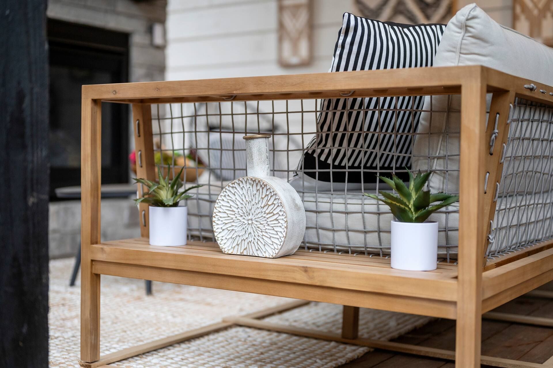Teak outdoor sofa with striped pillows and potted plants on the covered deck