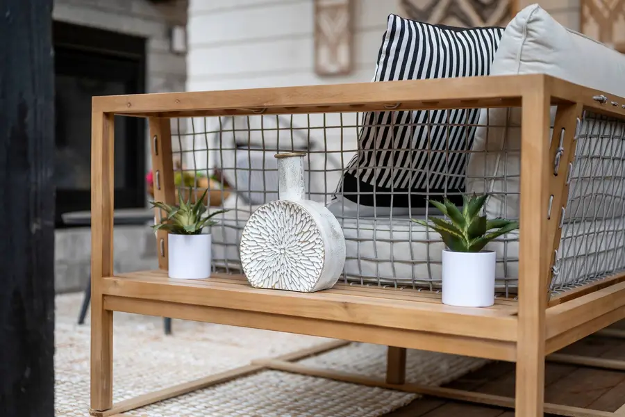 Teak outdoor sofa with striped pillows and potted plants on the covered deck