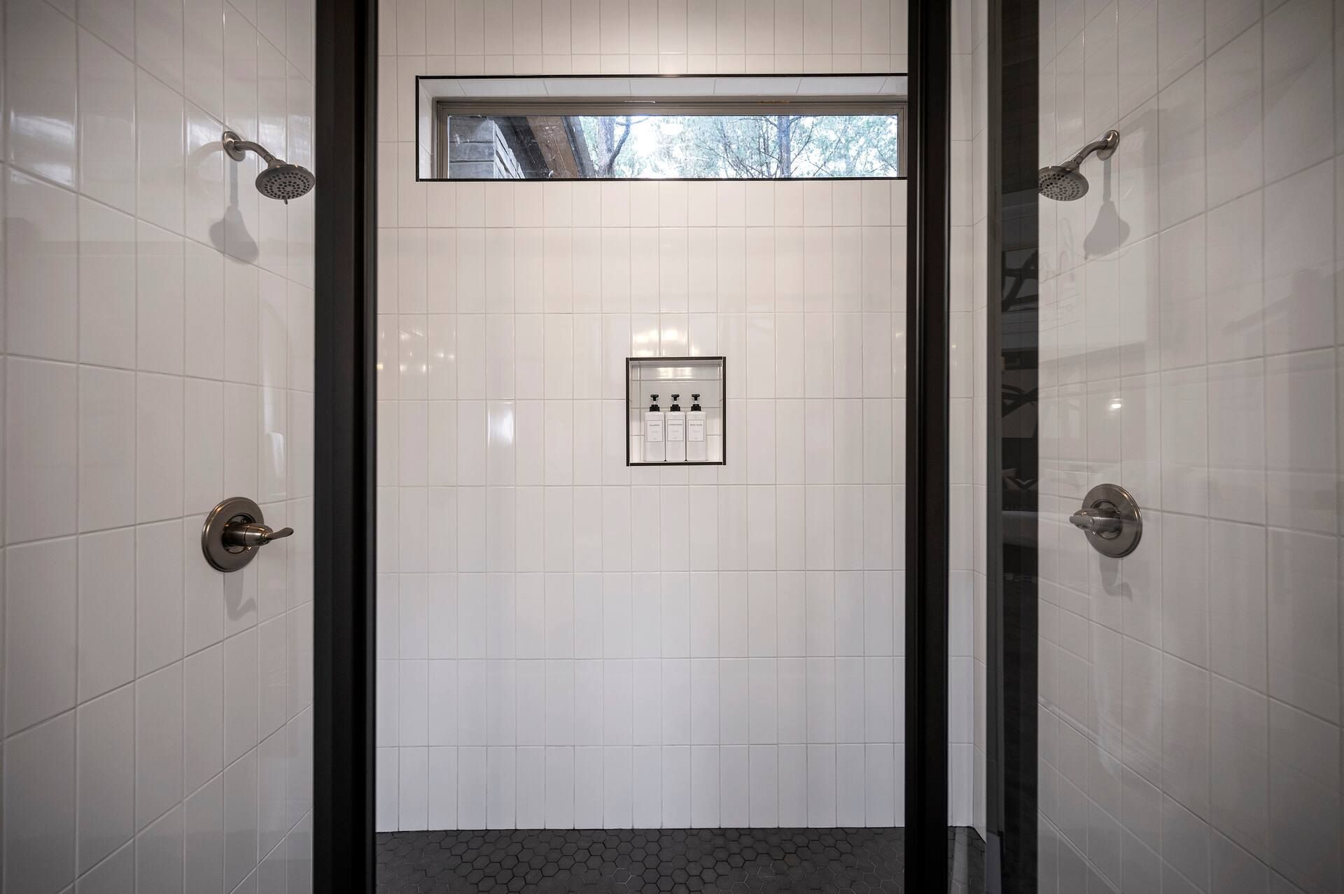 White tiled walk-in shower with two rain shower heads
