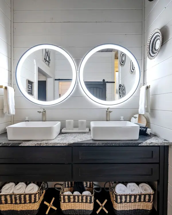 Bathroom double vanity with two lighted round mirrors, vessel sinks and woven wall baskets