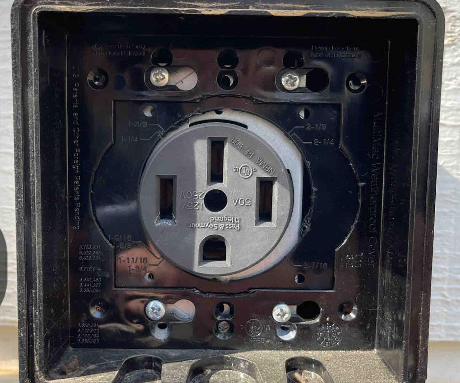 Weatherproof 50-amp NEMA 14-50 outlet on the cabin wall for EV charging