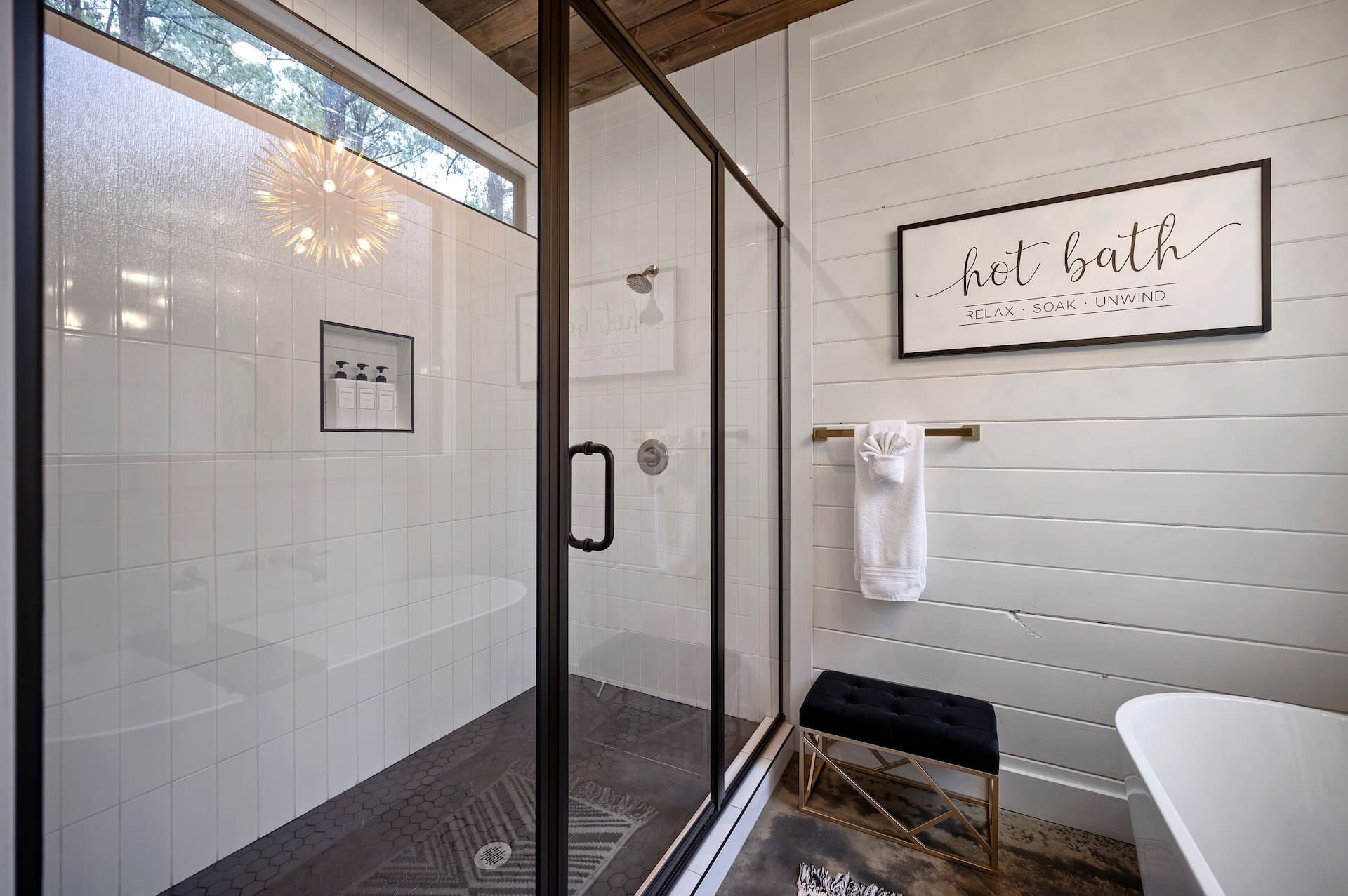 Glass walk-in shower beside the freestanding soaking tub and hot bath sign