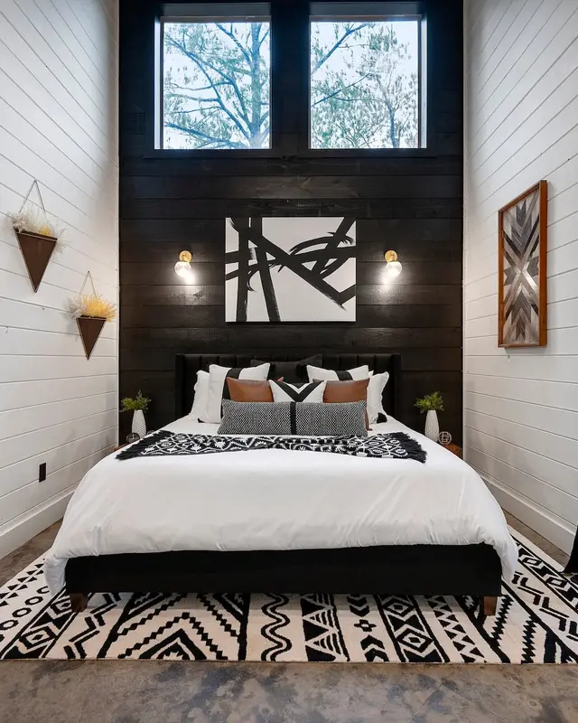 King bedroom with a black accent wall and tall windows to the trees