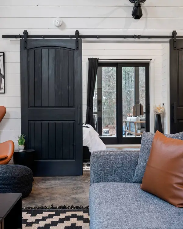 Living room with the black barn doors open to the bedroom, a leather egg chair and the gray sofa