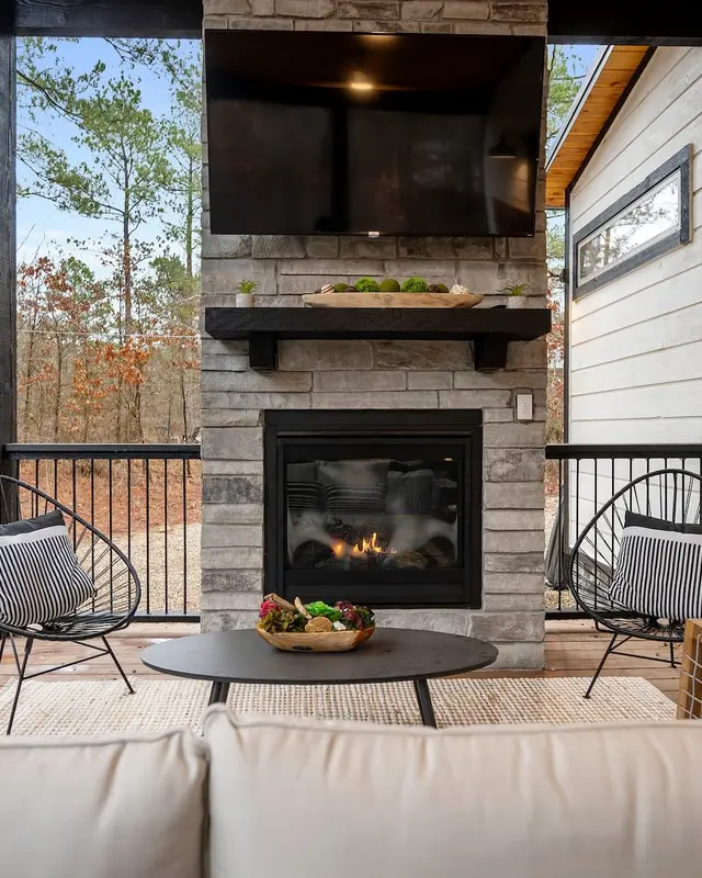 Outdoor stone fireplace on the covered deck with a TV above it