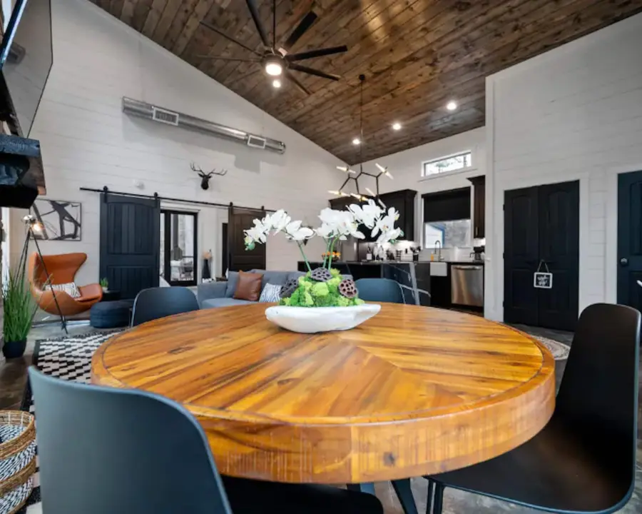 Round wood dining table between the kitchen and living room